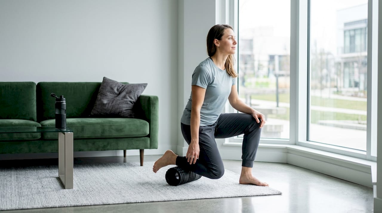 Assise dans un salon baigné de lumière, une femme prend soin de ses jambes en les massant doucement.