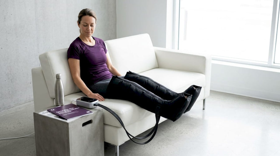 Un homme se détend dans son salon tout en profitant des bienfaits de ses bottes de compression.