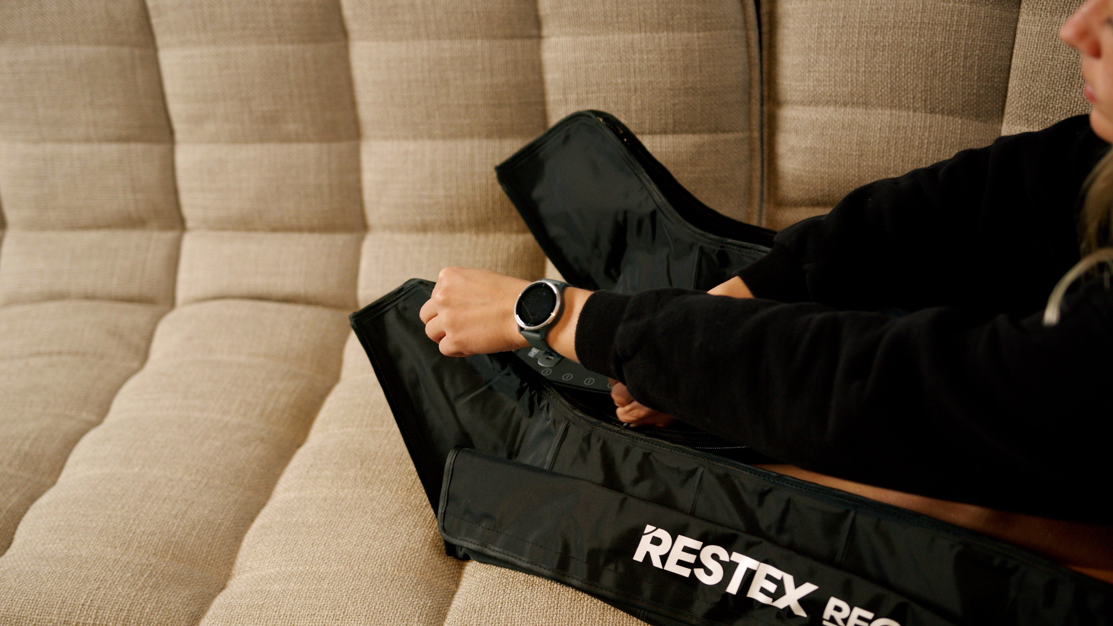 Bottes de pressothérapie Restex Recovery portées confortablement sur un canapé