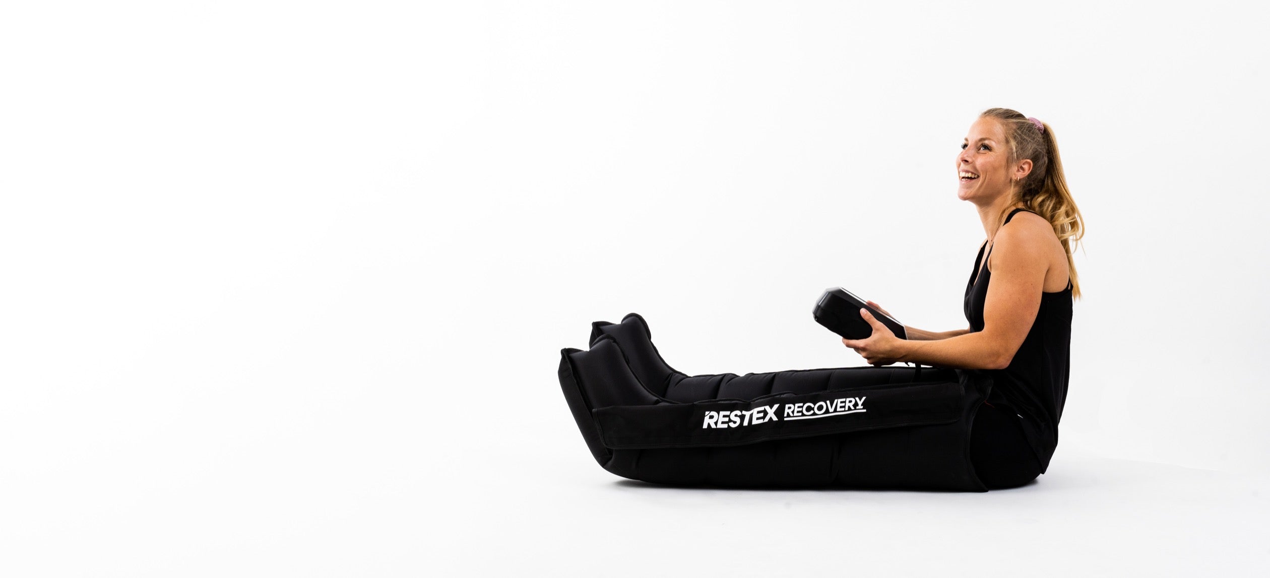 Femme souriante portant les bottes de pressothérapie Restex Recovery pour un drainage lymphatique à domicile