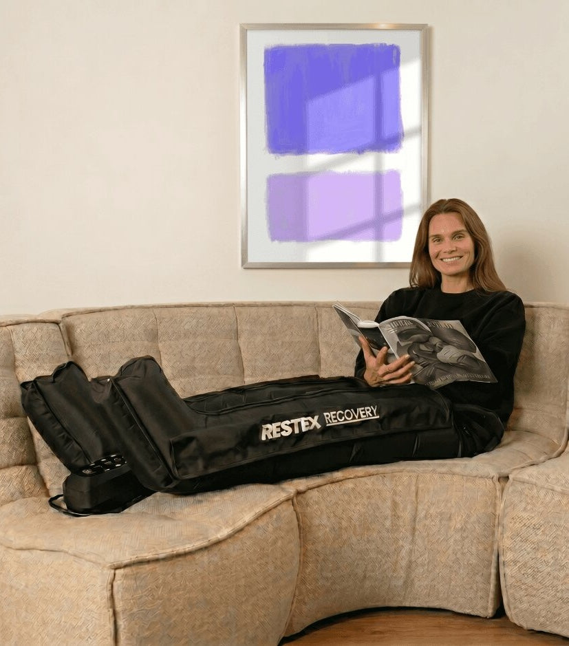Femme souriante en séance de pressothérapie Restex Recovery sur canapé — qualité cabinet à domicile